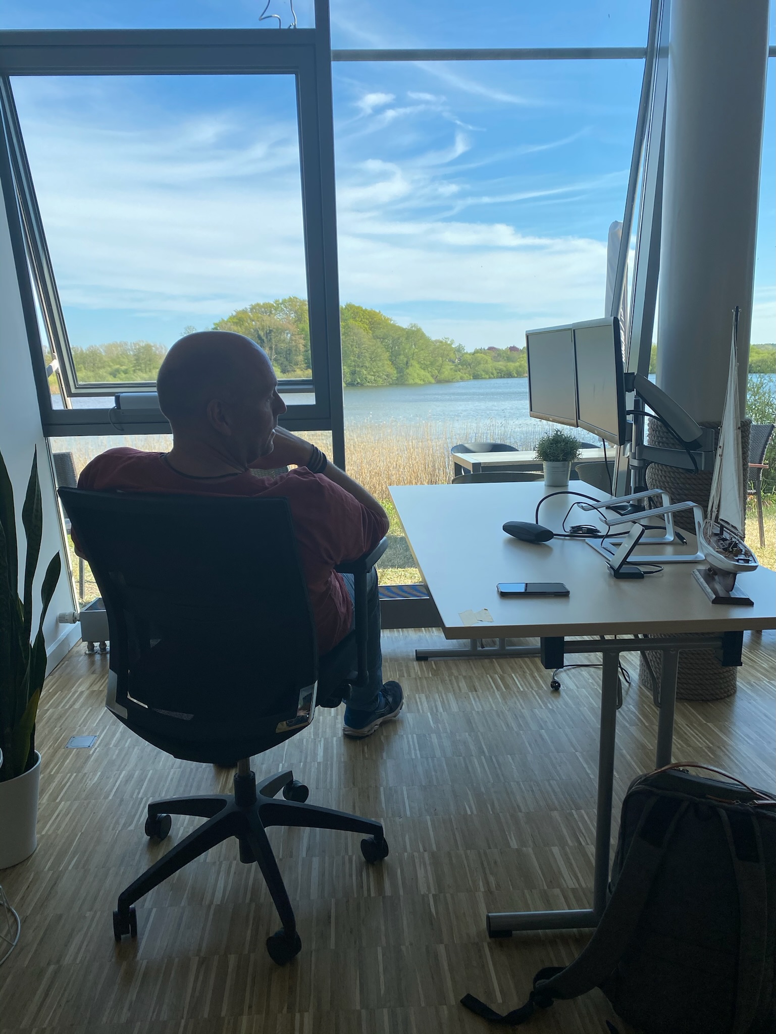 CoWorker an einem Arbeitsplatz mit zwei Monitoren und direktem Blick auf den Schulensee